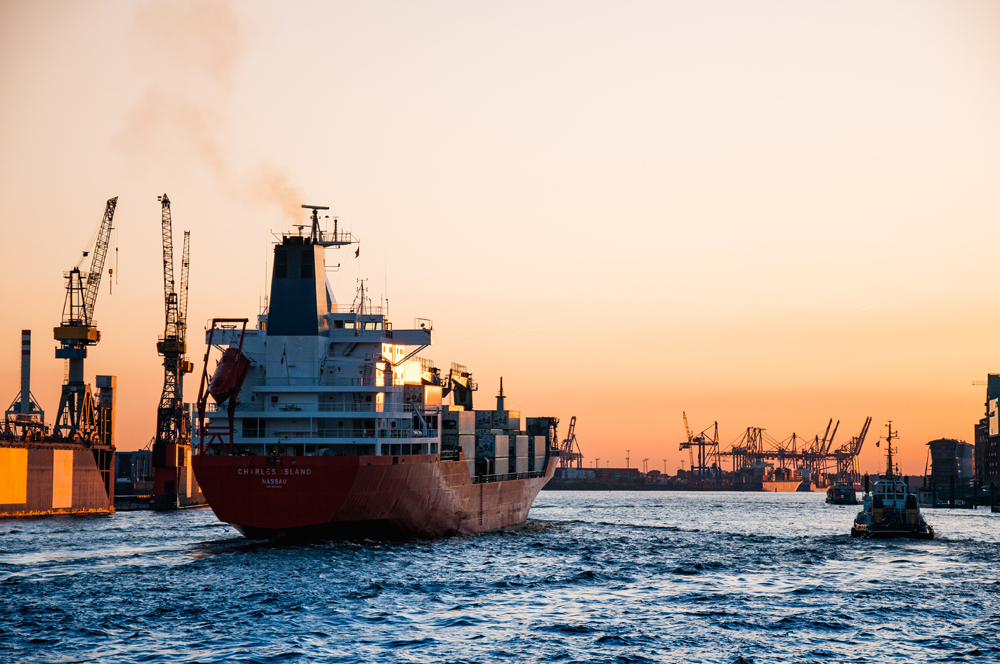 Ein rotes Dampfschiff, welches vom Hafen aufs Meer fährt.